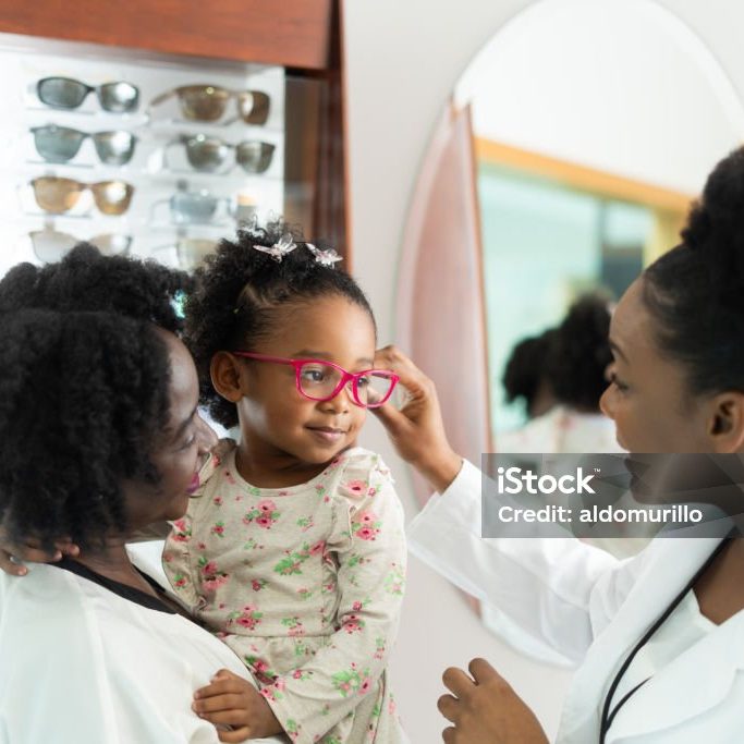 With the doctor's assistance, the little girl embraces her new glasses, reflecting newfound confidence and a fresh perspective on her vision and personal style.
